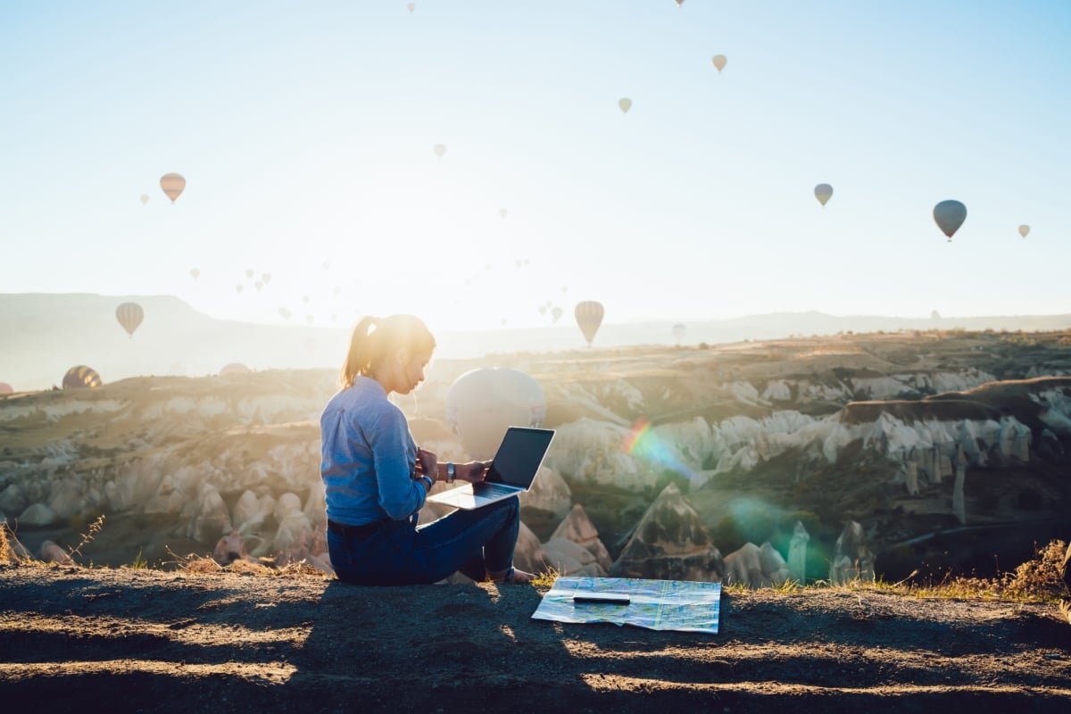 Woman working on laptop and watching hot air baloons in Turkiye